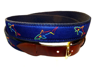 Boys classic ribbon shark belt is framed  in a great blast of colors in a Shark pattern. The sharks are repeated at all angles across the ribbon outlined in orange, green, and red on a dark royal background.   The belt is completed with leather tabs and a brass buckle.      