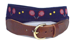 Men's  Pickleball Belt is a Design by Lillie Exclusive. Two red racquets and yellow balls sit on navy ribbon and navy canvas webbing. It is finished with leather tabs and a brass buckle. Size: 30-54